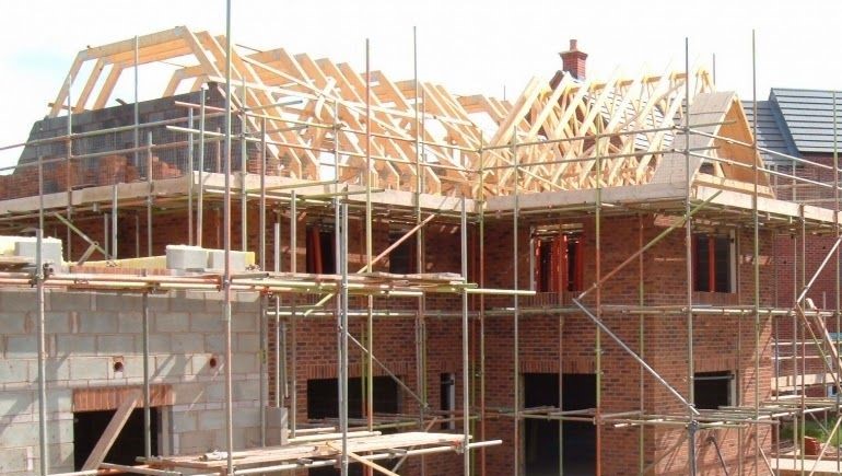 Pekerja konstruksi sedang membangun rumah minimalis modern di Jakarta dengan material berkualitas tinggi dan pengawasan profesional.