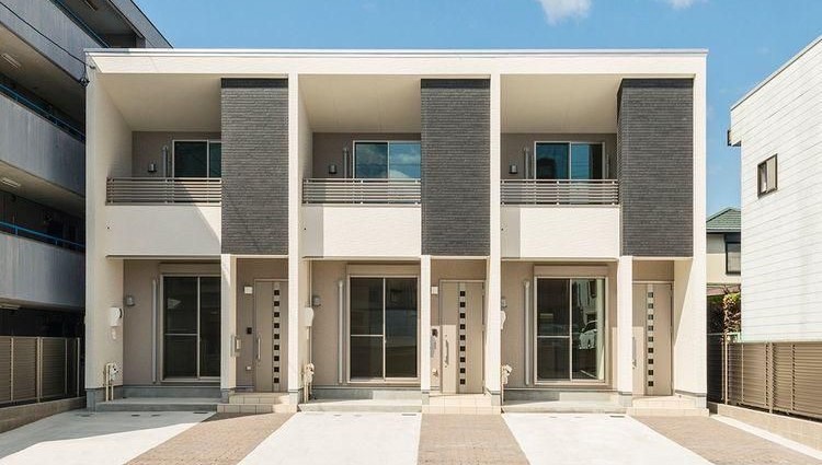 Tampilan ruko modern dengan fasad ACP minimalis warna cream dan abu-abu.